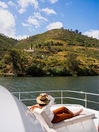 A traveller relaxing on the deck of a boat in the Douro Valley among the vineyards