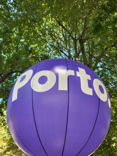 Purple 'Porto.' balloon floating among the trees at the Feira do Livro do Porto