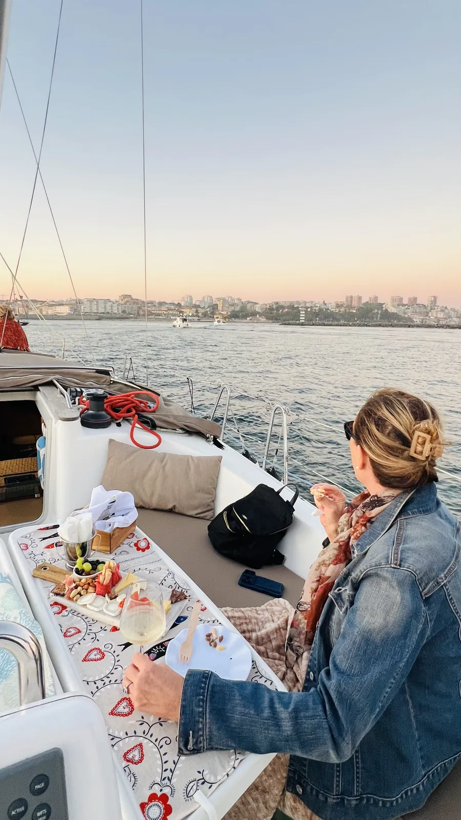 Guest enjoying a picnic spread on deck with the Porto coastline behind on a daytime cruise