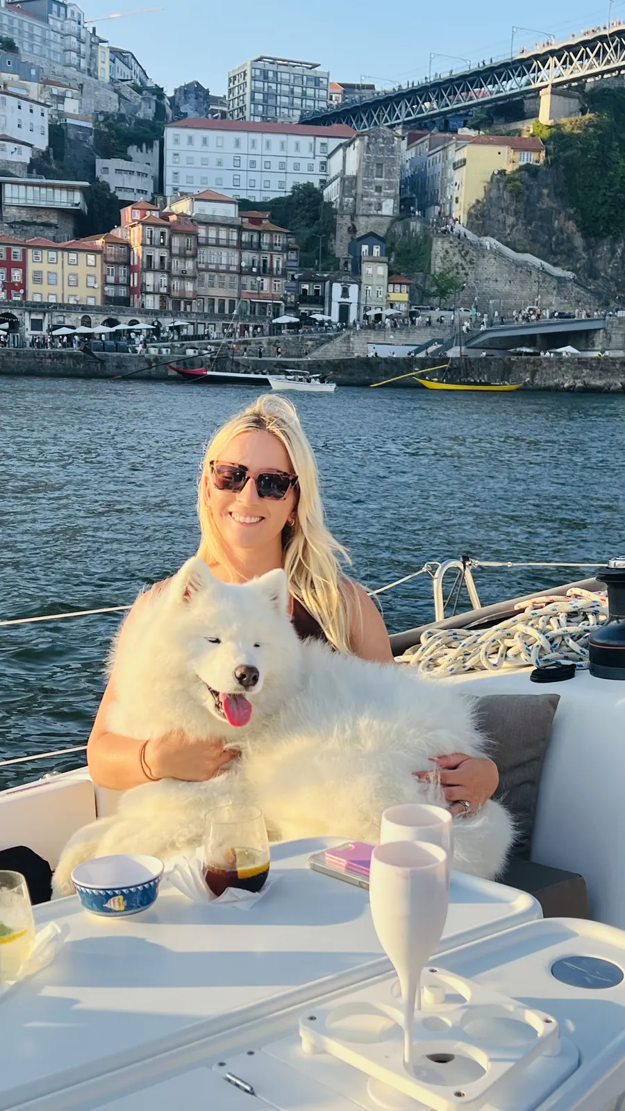 Guest and a white Samoyed dog on a dog-friendly sailboat in front of Porto Ribeira and the Douro