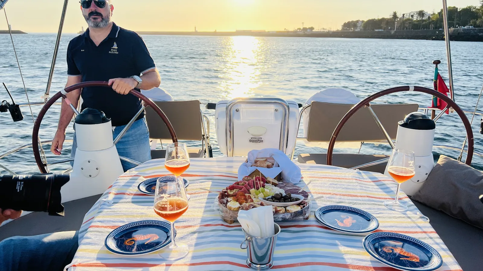 Captain at the helm beside a laid table on a private Porto sunset cruise on the Douro