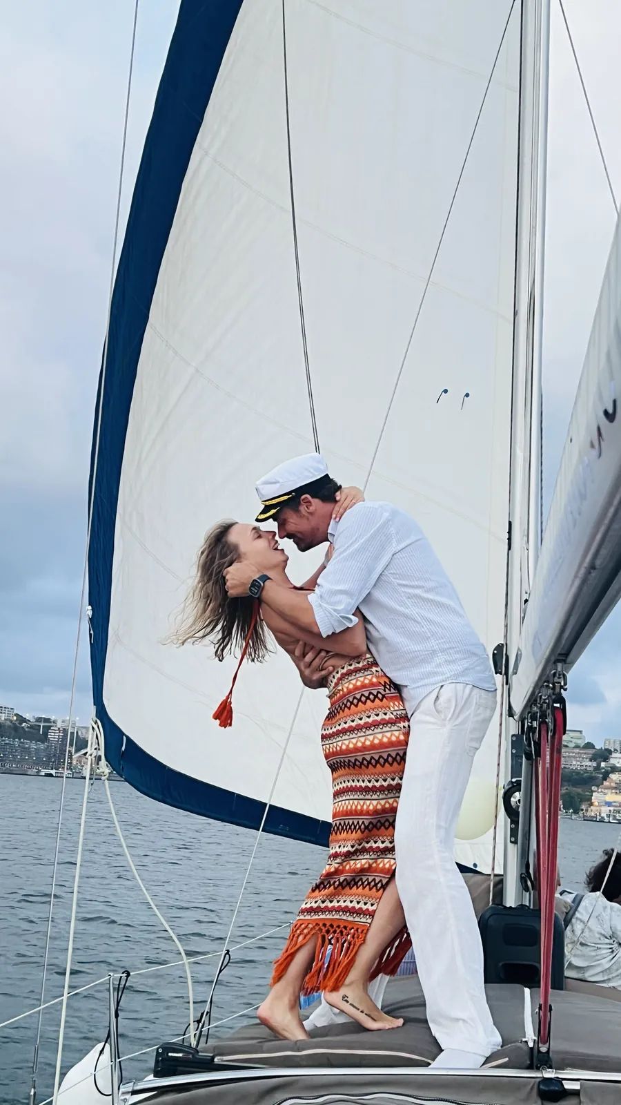 Couple embracing under the white sail on a romantic Porto sailing cruise