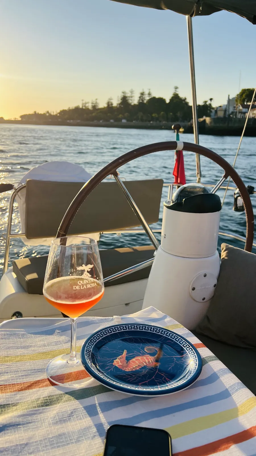 Rosé wine and a seafood appetiser served on deck beside the Portuguese flag at sunset