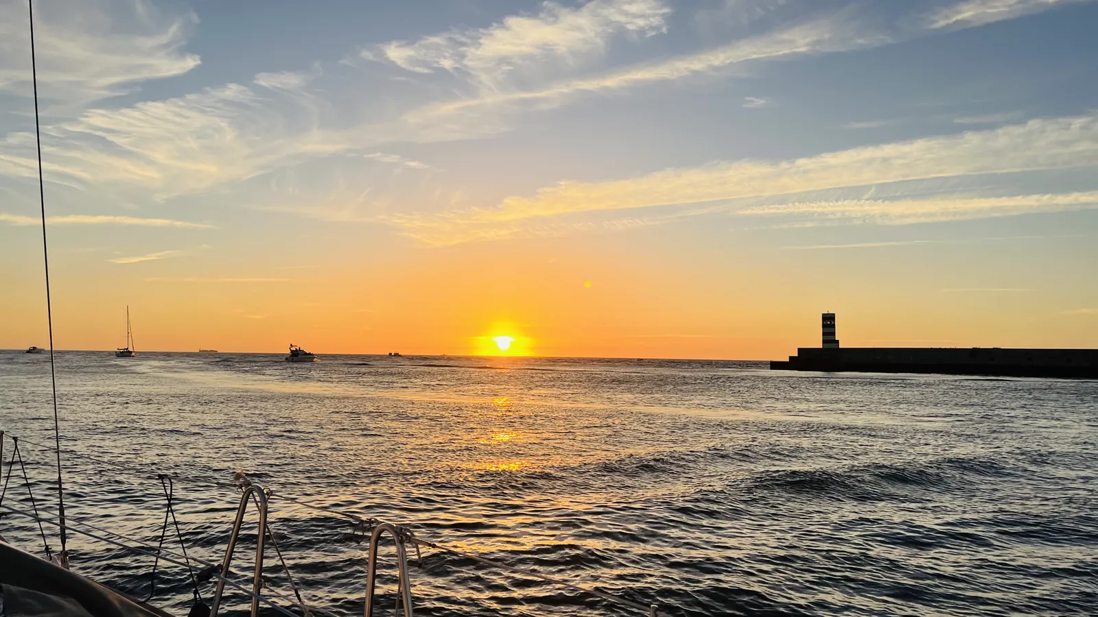 Wide Atlantic sunset with a lighthouse seen from a Porto sailing cruise