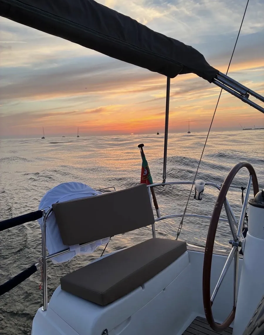 Sailboat helm and cockpit bathed in golden sunset light on a Porto cruise