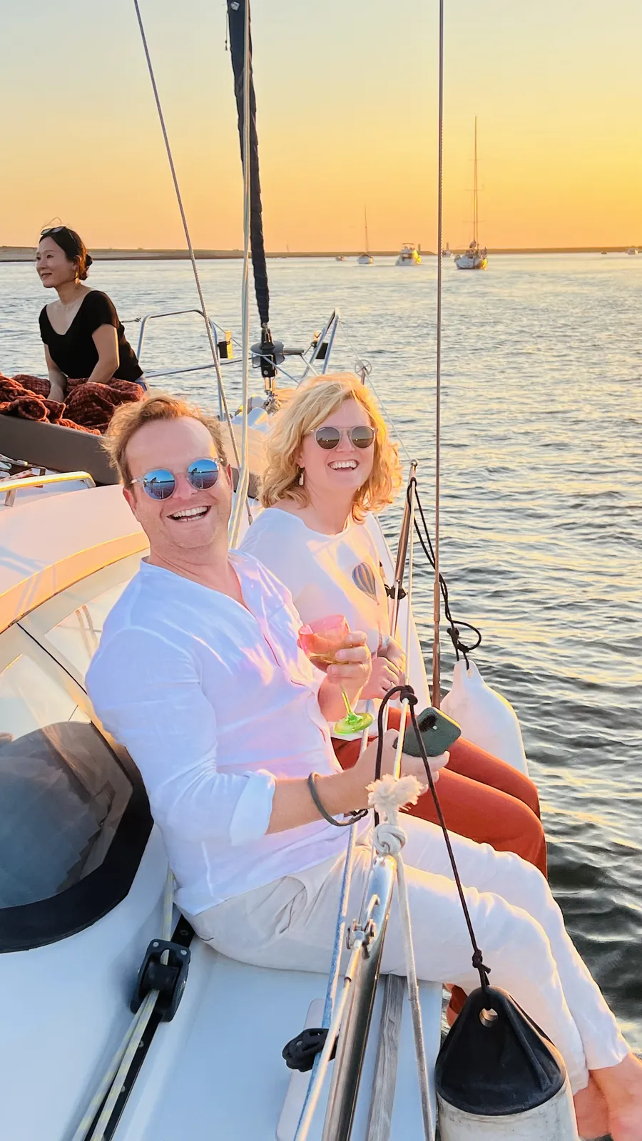 Two friends celebrating with drinks on deck during a sunset sail in Porto