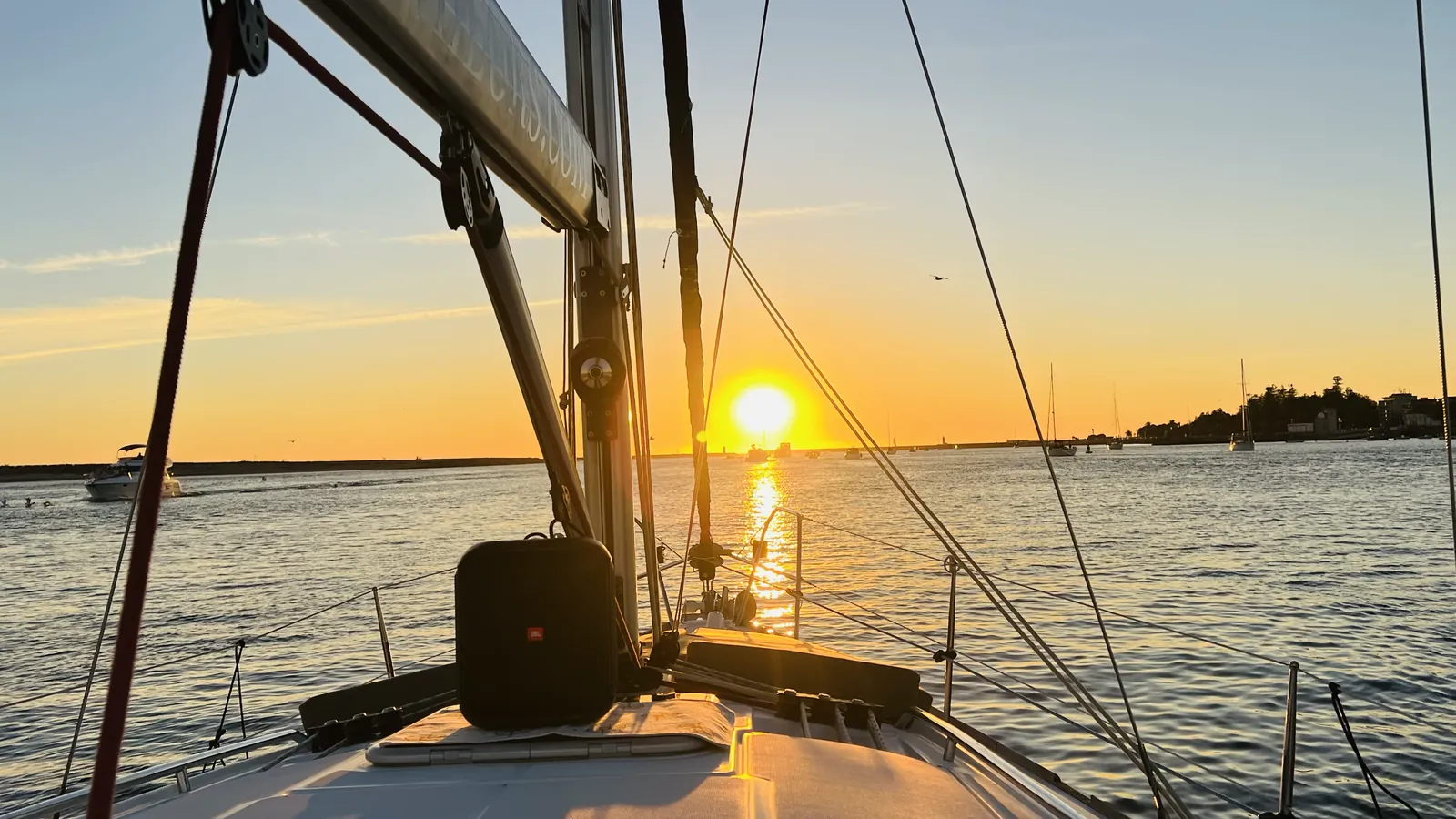 Golden-hour sunset through the rigging from the bow of a Porto sailboat