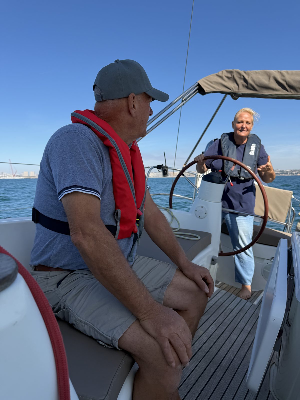 A guest takes the helm alongside the skipper on a Port Sailors sailboat off Porto